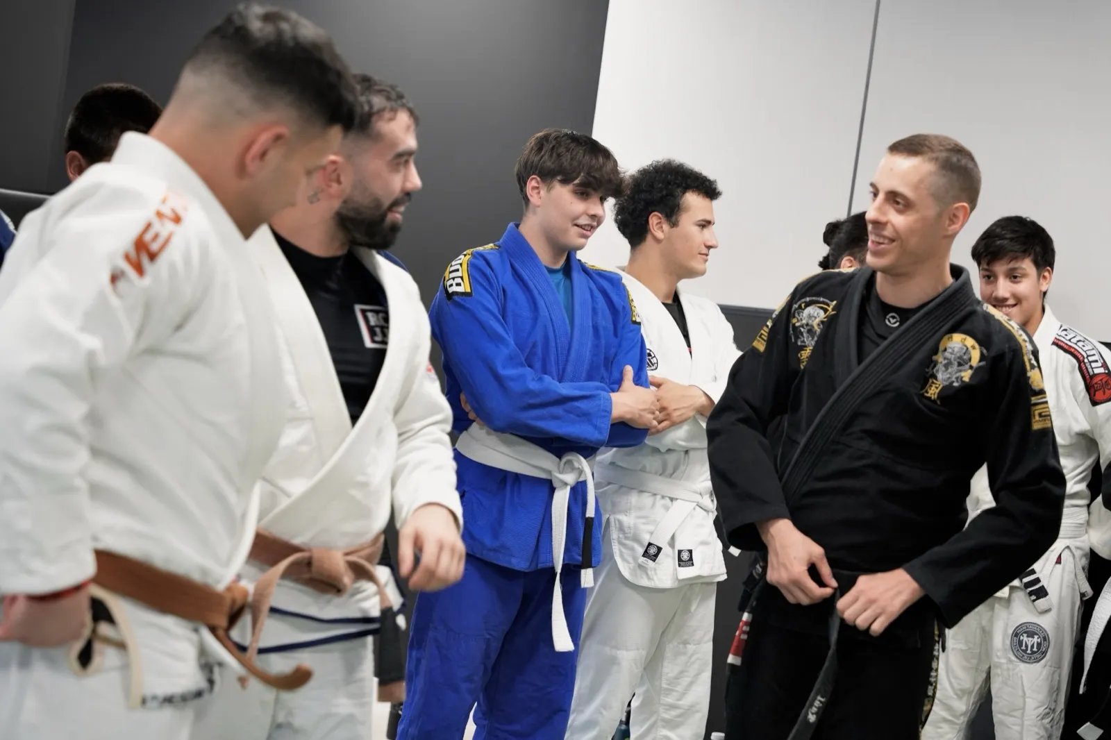 Raúl, instructor de NEKO, charlando y sonriendo con un grupo de alumnos con kimono antes de entrenar Jiu-Jitsu en Madrid